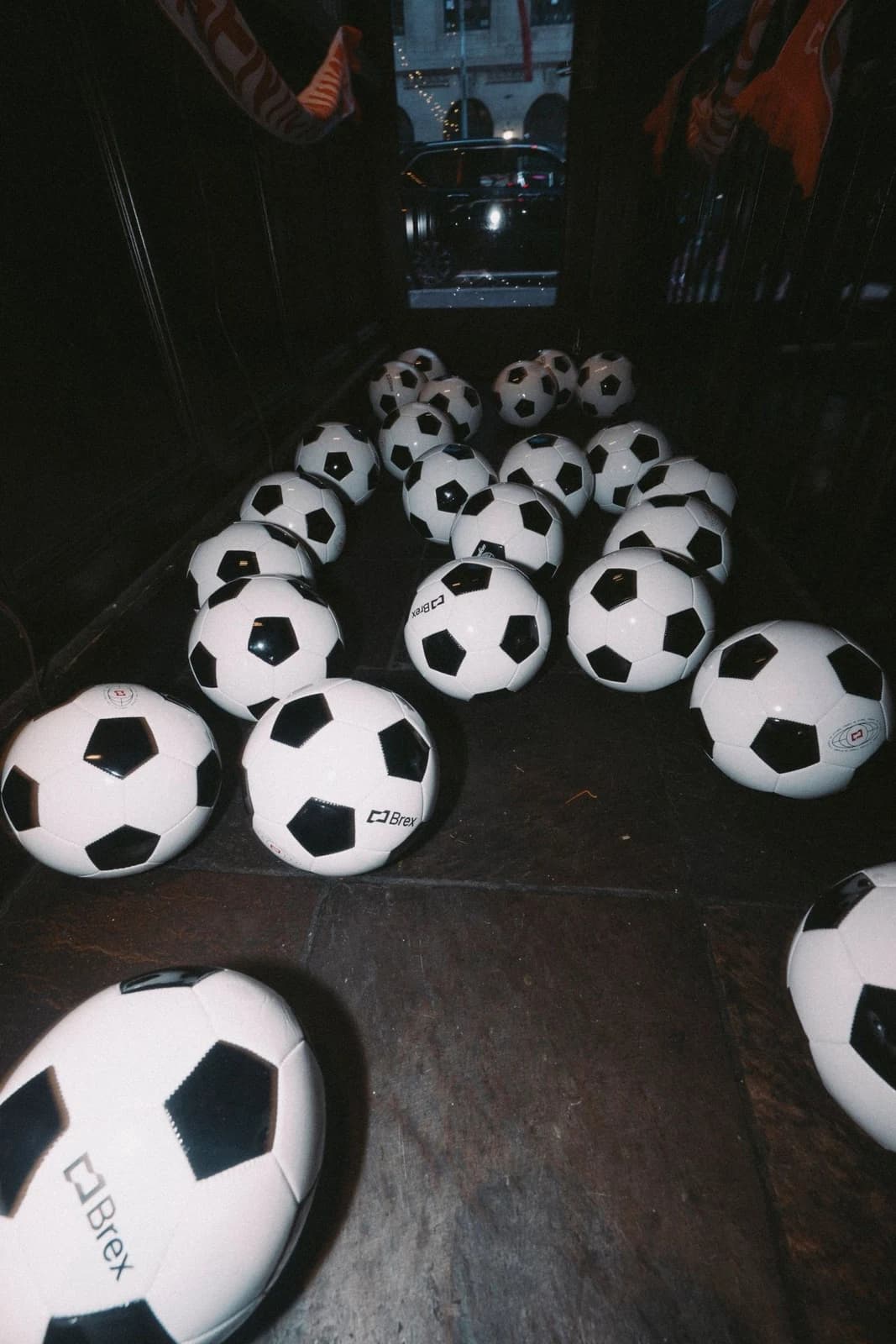 Brex-branded soccer balls in a dark interior